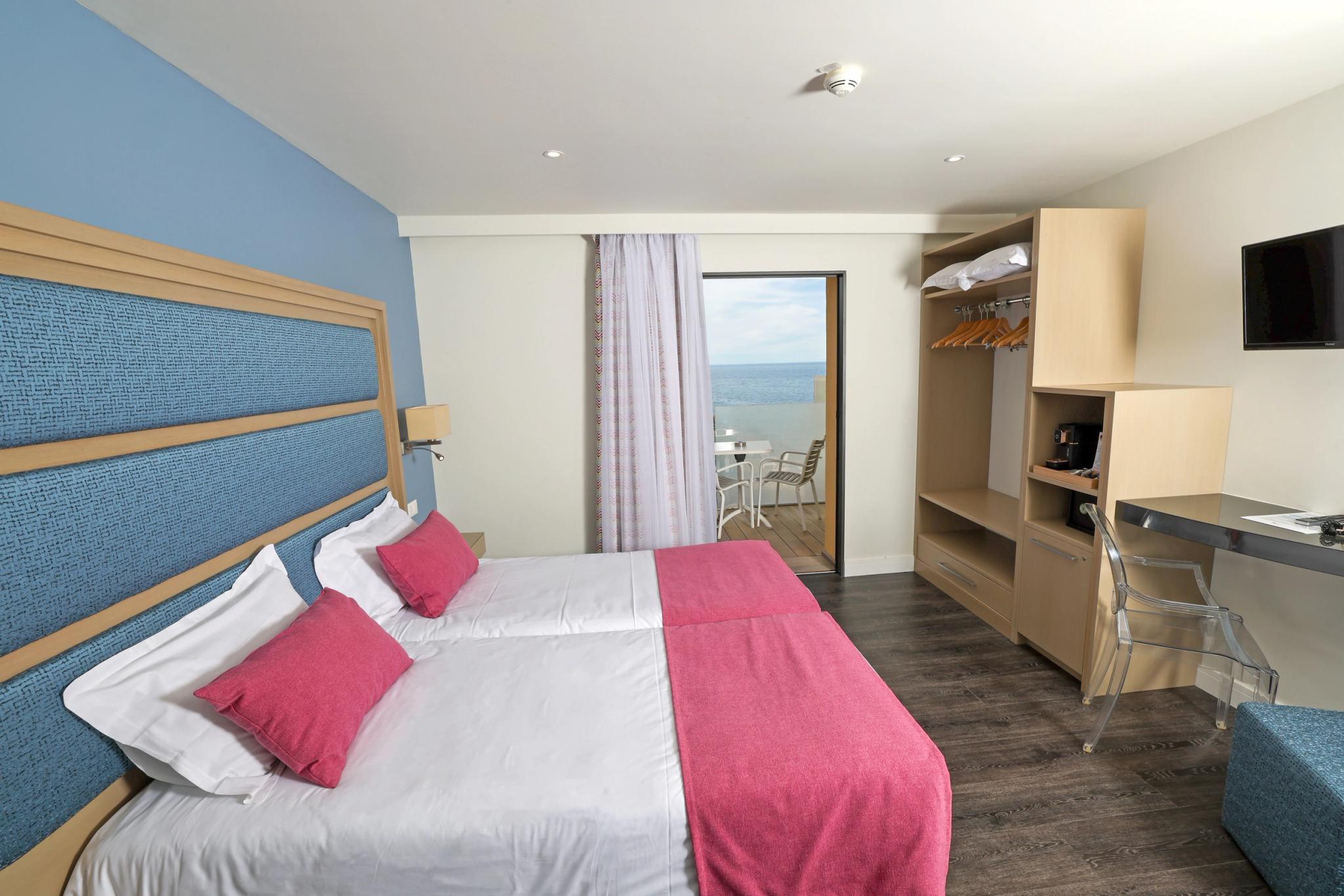 Lit double en configuration twin dans une chambre lumineuse avec ouverture sur une terrasse